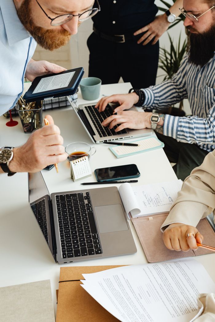 who-we-are Teamwork in action with technology, papers, and collaboration at a dynamic office desk.